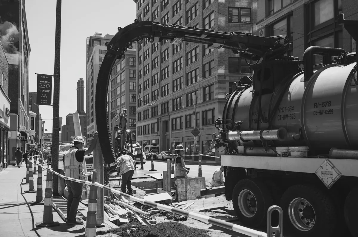 Vacuum excavation truck with its boom over a street excavation in a city